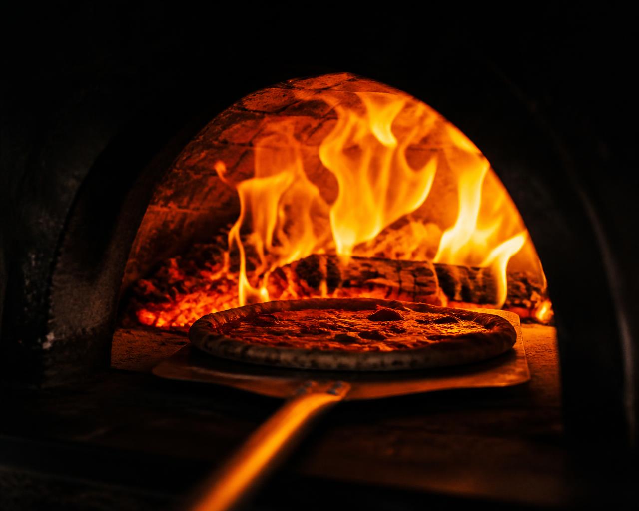 Pizza på spade på väg in i den brinnande ugnen